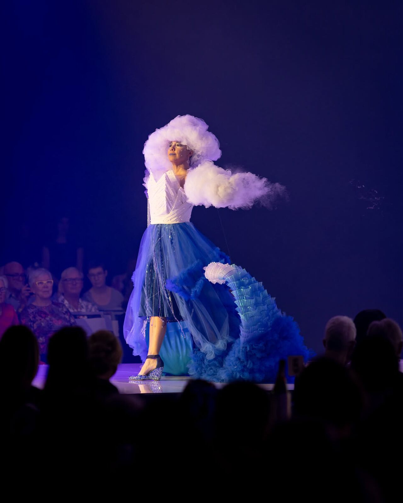 Alpha on stage in a blue and white gown