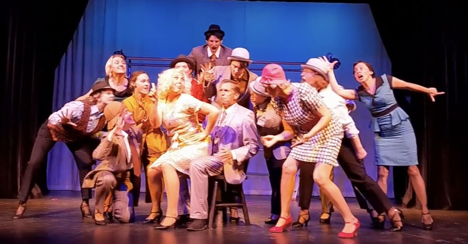 A theatre cast on stage mid scene