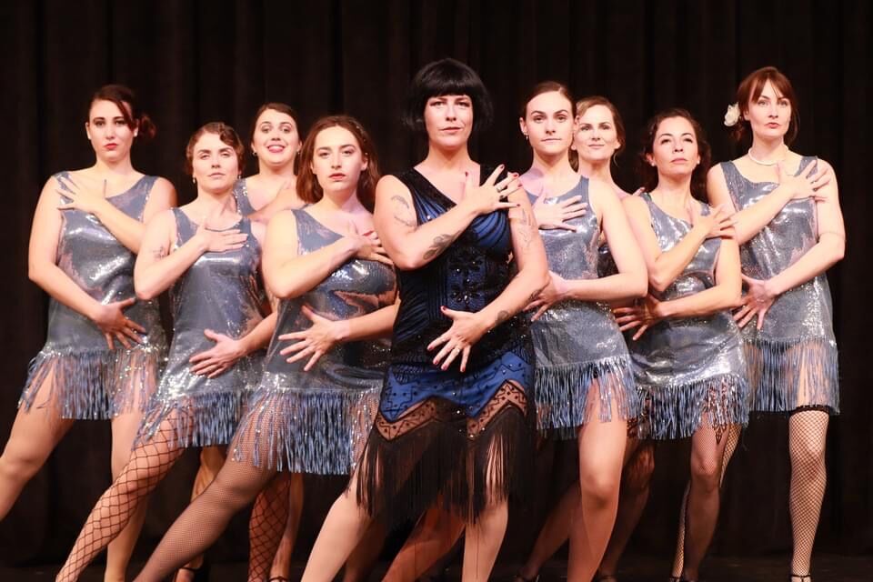 A line of performers in flapper dresses